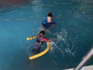 Young boy in pool with yellow swimming aid