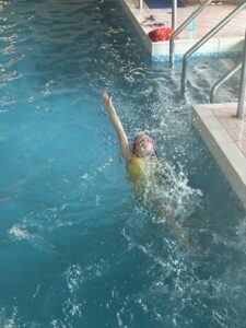 Young girl in pool doing backstroke