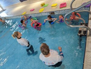 STA Gold Accredited Swim School Swim With Me swimming lesson with several children in pool